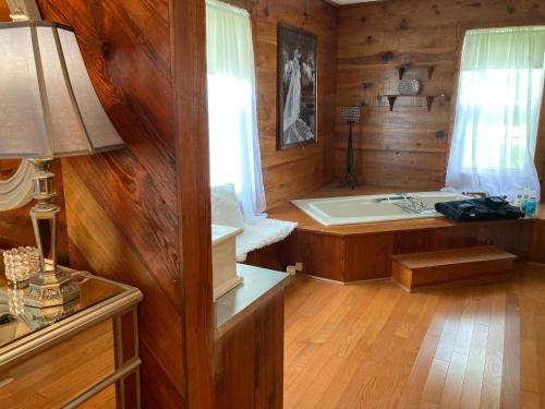 ein Bad mit Badewanne in einem Zimmer mit Holzwänden in der Unterkunft Lazy Dog Acres 