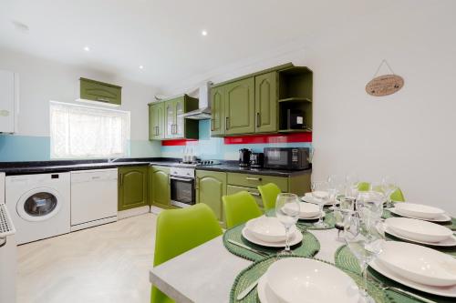 a kitchen with green cabinets and a table with green chairs at 5BR House, Free Parking offA12, Contractor, Big Families, Relocation in Redbridge