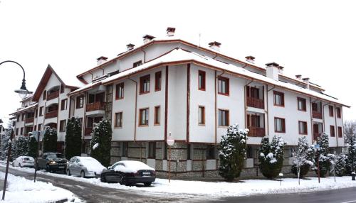 a large white building with cars parked in the snow at Pirin River Ski, Fun and Family in Bansko