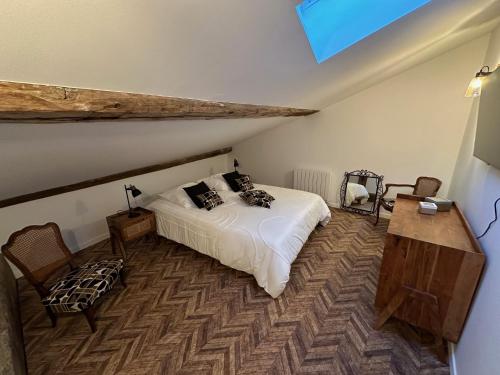 a bedroom with a white bed and a wooden table at La maison du village in Romanèche-Thorins