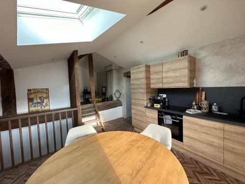 - une cuisine avec une table en bois et des chaises blanches dans l'établissement La maison du village, à Romanèche-Thorins