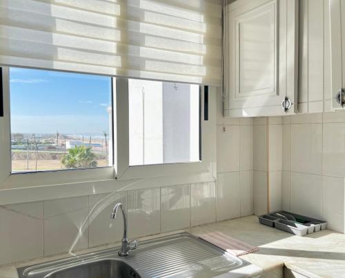 uma cozinha com um lavatório e uma janela em Appartement face à la mer et à 10min du centre-ville em Casablanca
