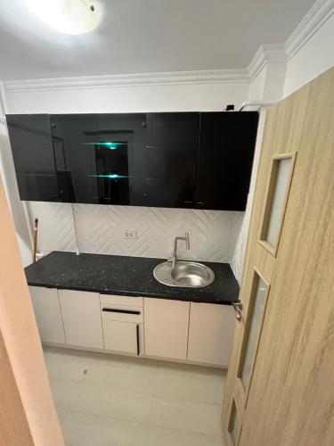 La salle de bains est pourvue d'un lavabo et d'un comptoir noir. dans l'établissement Apartament 1 camera Brăila(hipodrom), à Brăila