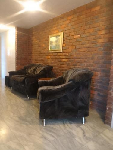 three leather couches are lined up against a brick wall at Blue Oasis Apartments in Benoni