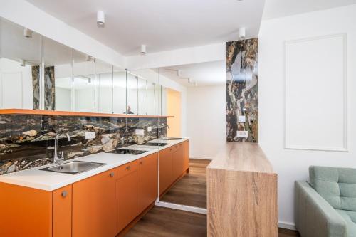 een keuken met oranje kasten en een blauwe bank bij City Center Design Apartments in Sarajevo