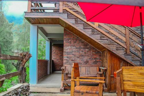 a red umbrella and some chairs and a building at Omah kayu bromo in Ngadisari