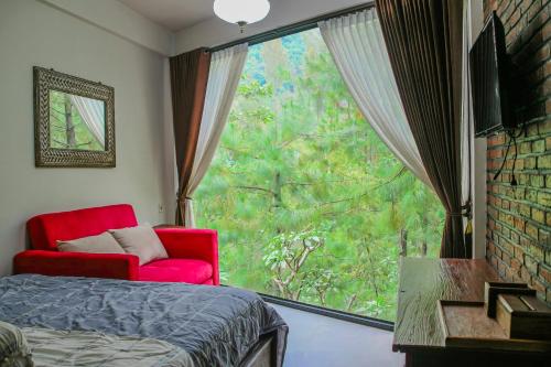 a bedroom with a red chair and a large window at Omah kayu bromo in Ngadisari