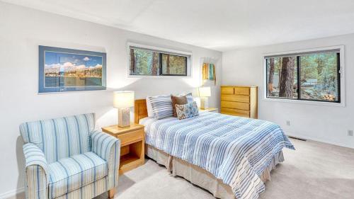 a bedroom with a bed and a chair and two windows at Shadow - Unit 1 in Sunriver