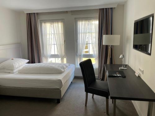 a hotel room with a bed and a desk and a bed and window at Das Goldene Lamm Aalen in Aalen