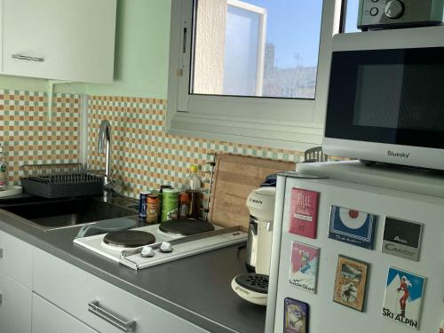 La cuisine est équipée d'une cuisinière, d'un four micro-ondes et d'un réfrigérateur. dans l'établissement Studio 20m² lumineux avec balcon - Cœur de Berck Plage, proche commerces et plage - FR-1-646-20, à Berck-sur-Mer