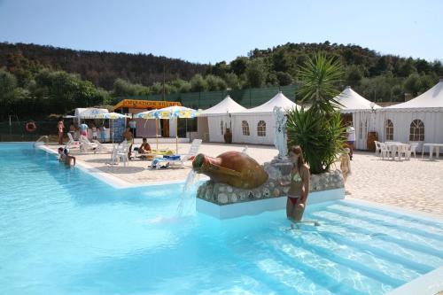 a woman standing in a swimming pool with a fountain at Camping La Gemma in Peschici