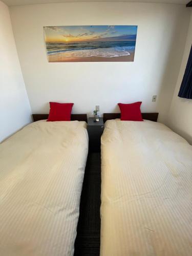 two beds in a small room with red pillows at MR TOMO FUJI in Fuji