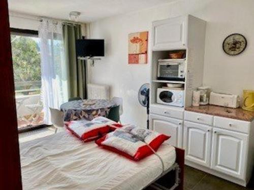 - une chambre avec un lit doté d'oreillers rouges dans l'établissement Studio cosy 24 m² avec balcon, proche cures et centre-ville, animaux bienvenus ! - FR-1-703-109, à Amélie-les-Bains-Palalda
