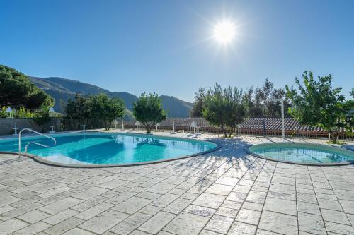 two swimming pools in a courtyard with trees and mountains at Agriturismo Nonno Luigino in Vico Equense