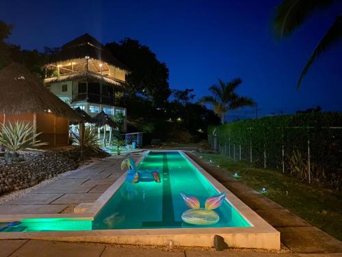 a swimming pool in front of a house at night at Hotel Vista Bonita in Parrita