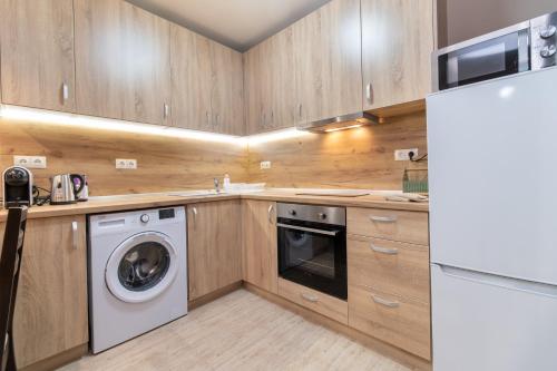 una cucina con armadi in legno, lavatrice e asciugatrice di City Central 1-Bed Apartments a Plovdiv