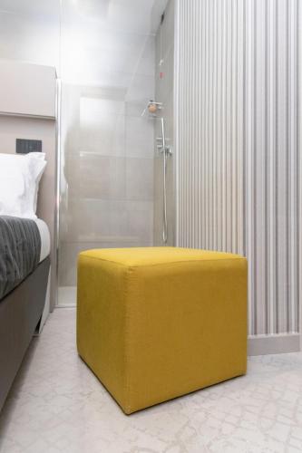 ein gelber Ottoman in einem Schlafzimmer mit Dusche in der Unterkunft Calypsosuite in Salerno
