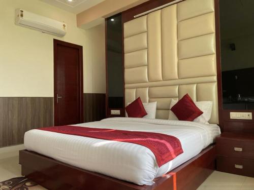 a bedroom with a large white bed with red pillows at Hotel Mannat International at Paschim Vihar in New Delhi