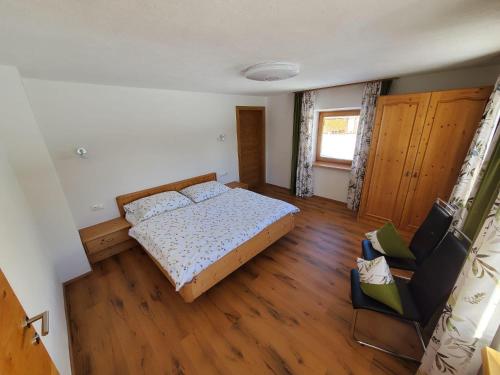 a bedroom with a bed and a chair in it at Rosa's Ferienhaus Ferienwohnung Rote Flueh in Grän