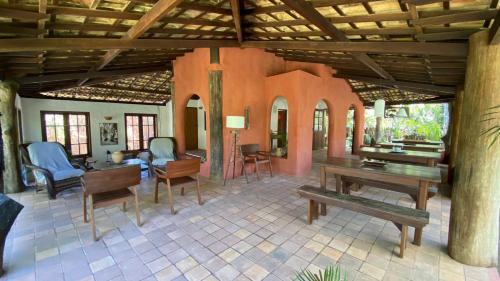 una sala de estar con mesas y sillas en una casa en Pousada Flor Do Mar, en Caraíva