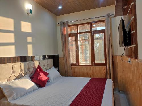 a bedroom with a bed with red pillows and a television at Vintage Woods Inn in Shimla