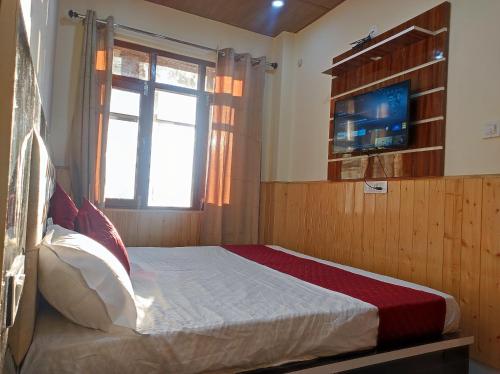 a bedroom with a bed with a television and a window at Vintage Woods Inn in Shimla