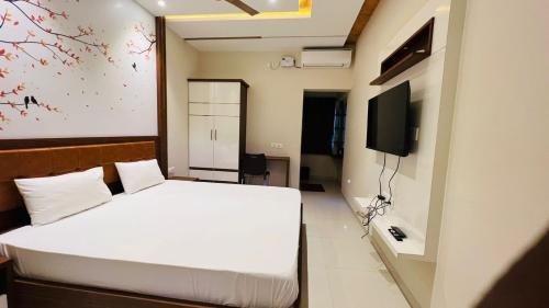 a bedroom with a white bed and a tv at NKP Residency in Alāndurai