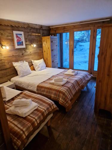 1 dormitorio con 2 camas y ventana en Alpina Lodge Chalet By Valdiski, en Val dʼIsère