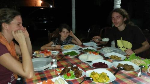 a group of people sitting around a table with food at New Gama Guest in Polonnaruwa