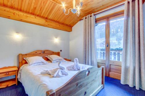 une chambre avec un lit et une grande fenêtre dans l'établissement l'OUTO, à Morzine