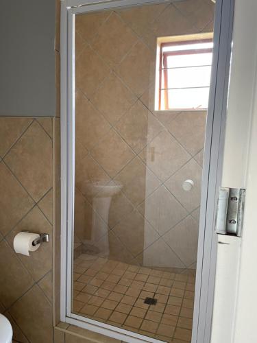 a shower with a glass door in a bathroom at Witbank Apartments in eMalahleni