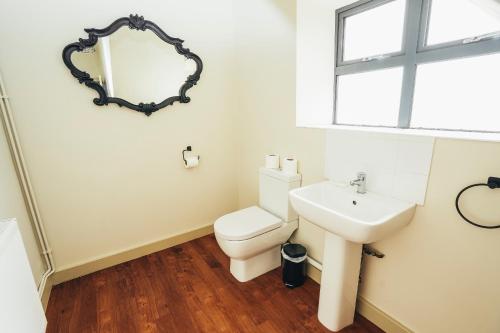 ein Badezimmer mit einem Waschbecken, einem WC und einem Spiegel in der Unterkunft Cottages In Derbyshire, The Farm House in Belper