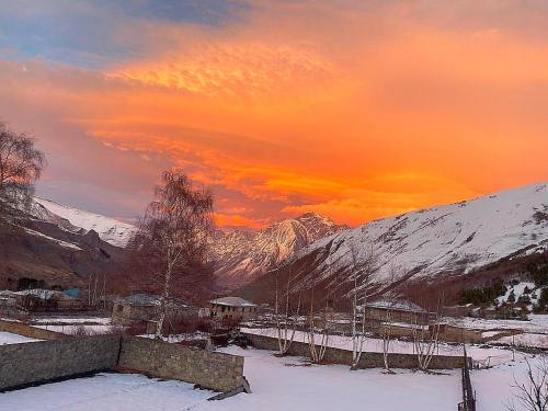 una puesta de sol sobre una montaña cubierta de nieve con un campo cubierto de nieve en Garemta, en Kazbegi