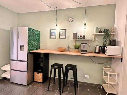 La cuisine est équipée d'un comptoir avec tabourets et d'un réfrigérateur. dans l'établissement Urban & Chic: 2Bdr, Parkplatz, à Witten