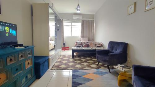 uma sala de estar com um sofá e uma cadeira e uma televisão em Studio Canadá: Custo-Benefício $ em Florianópolis