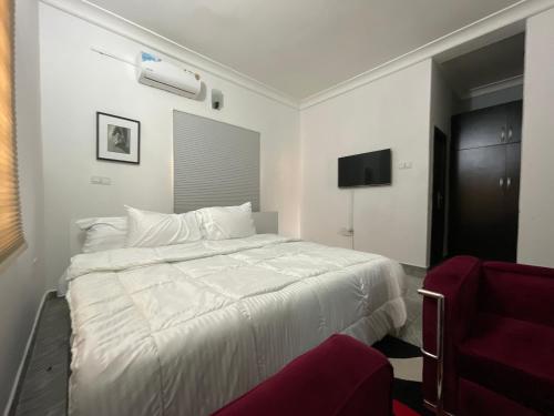 um quarto com uma cama branca e uma cadeira vermelha em Joda’s apartment em Lagos