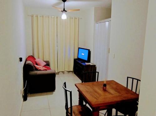 uma sala de estar com uma mesa, um sofá e uma televisão em Apê Expô/ABQM - Cantinho Moraes em Araçatuba