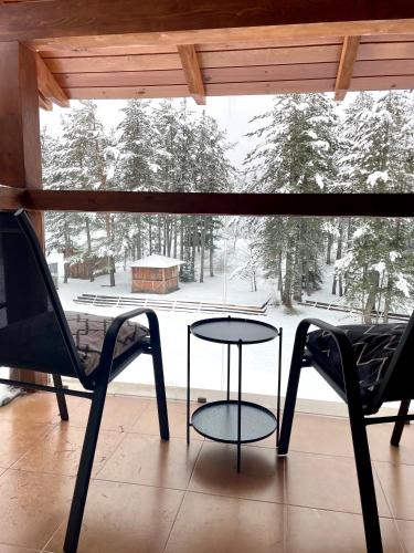 a table and two chairs on a porch with a snow covered yard at Spacious penthouse chalet apartment in Pirin Golf and Country Club in Razlog