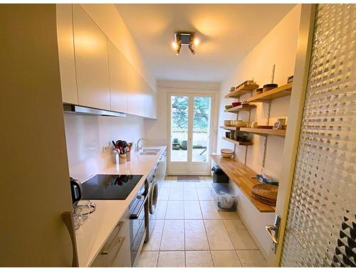 eine Küche mit weißen Schränken und einem großen Fenster in der Unterkunft L'Appart' de Famille - 6 pers - Poitiers Centre in Poitiers