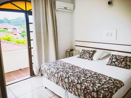 um quarto com uma cama e uma grande janela em Acqua Floripa Morro das Pedras SC em Florianópolis
