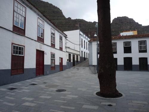 an empty street with white buildings and a tree at Meriga in Agulo