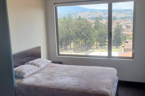 1 cama en un dormitorio con ventana grande en Departamento Expectacular en Cuenca