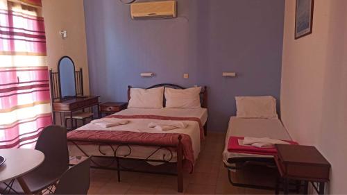 a bedroom with two beds and a table and a table at Corfu Sunflower Apartments in Benitses