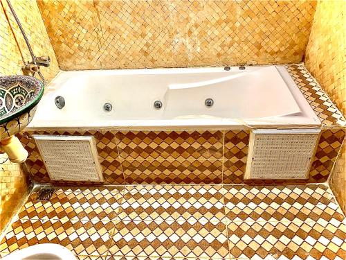 a bath tub in a bathroom with a tiled floor at Riad Nezha in Marrakech