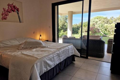 une chambre avec un lit et une porte coulissante en verre dans l'établissement Appartement en rez de jardin., à Porto-Vecchio