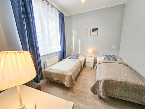 um quarto com 2 camas e uma janela em APARTAMENTY "LA VILLA" SUPERIOR III z prywatnym ogrodem, tarasem i parkingiem em Kudowa-Zdrój