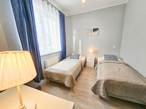 a bedroom with two beds and a window at APARTAMENTY "LA VILLA" SUPERIOR III z ogrodem, tarasem, parkingiem, blisko centrum in Kudowa-Zdrój
