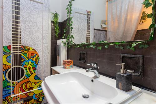 uma casa de banho com um lavatório e uma guitarra na parede em Lodge&Art Hostel em Trieste