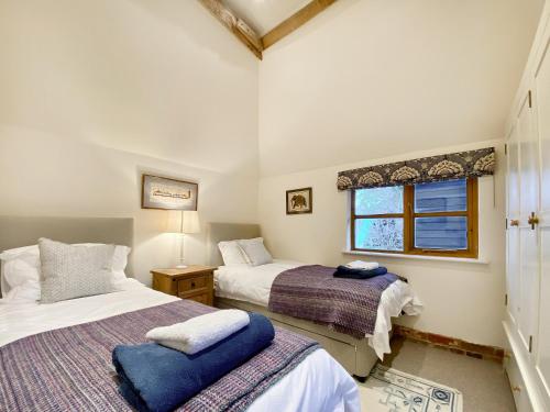 a bedroom with two beds and a window at Bushton Barn in Royal Wootton Bassett