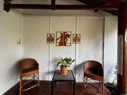 two chairs and a table with a plant on a wall at Roemah Uli Cirebon in Cirebon